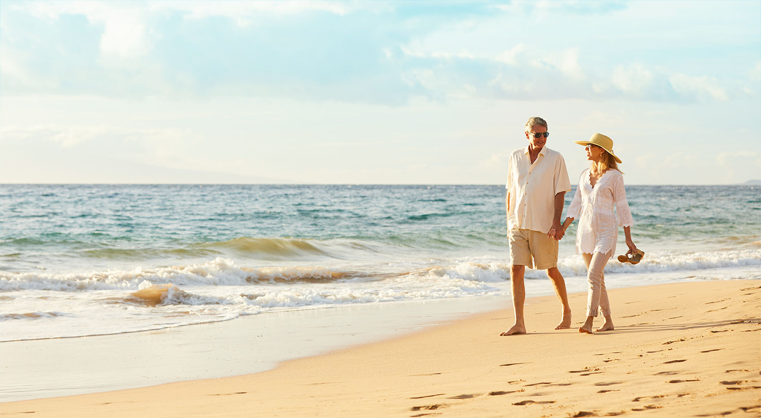 Mature couple walking together on a bright beach